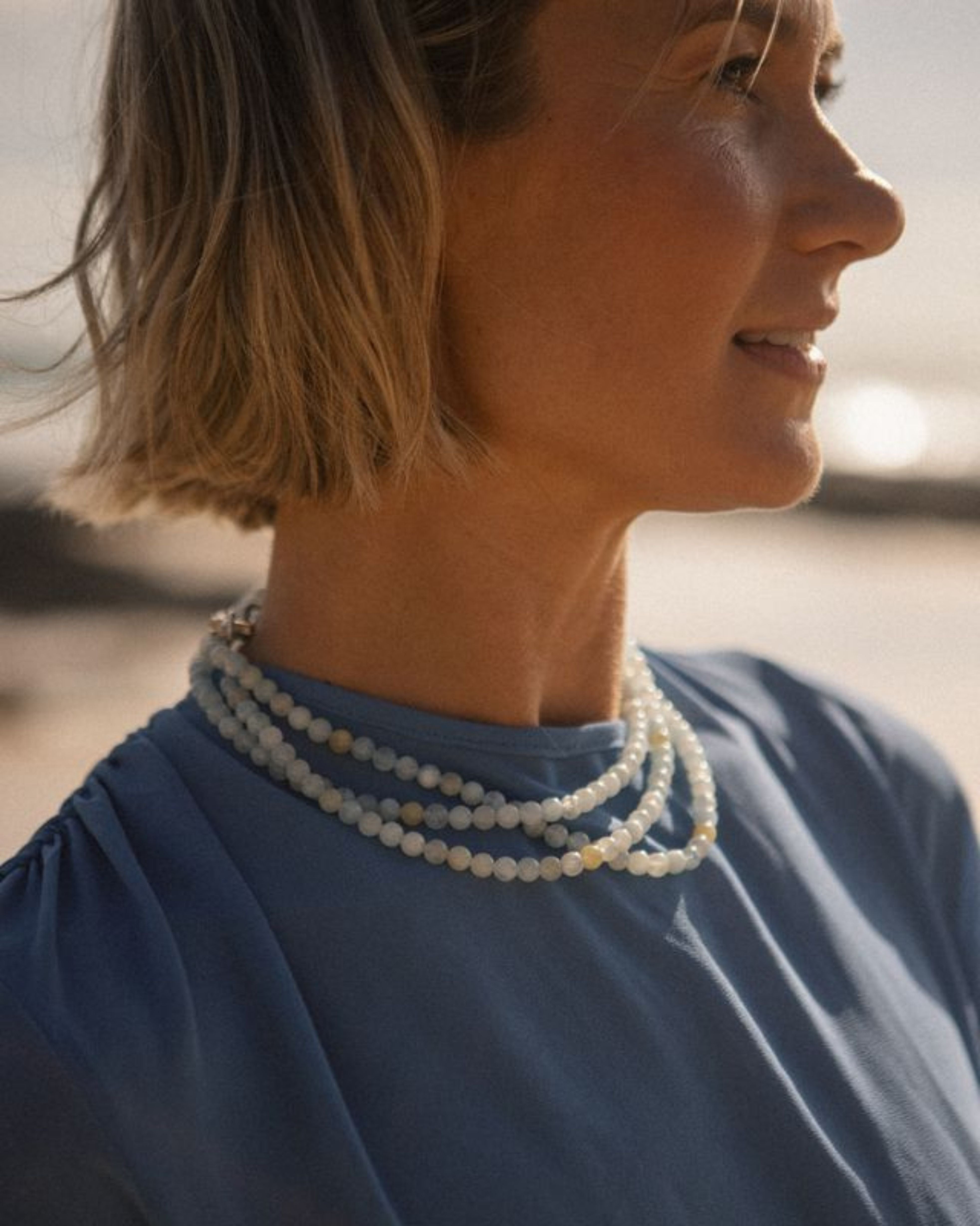 Woman wearing a aqua marine necklace with a blurred natural background