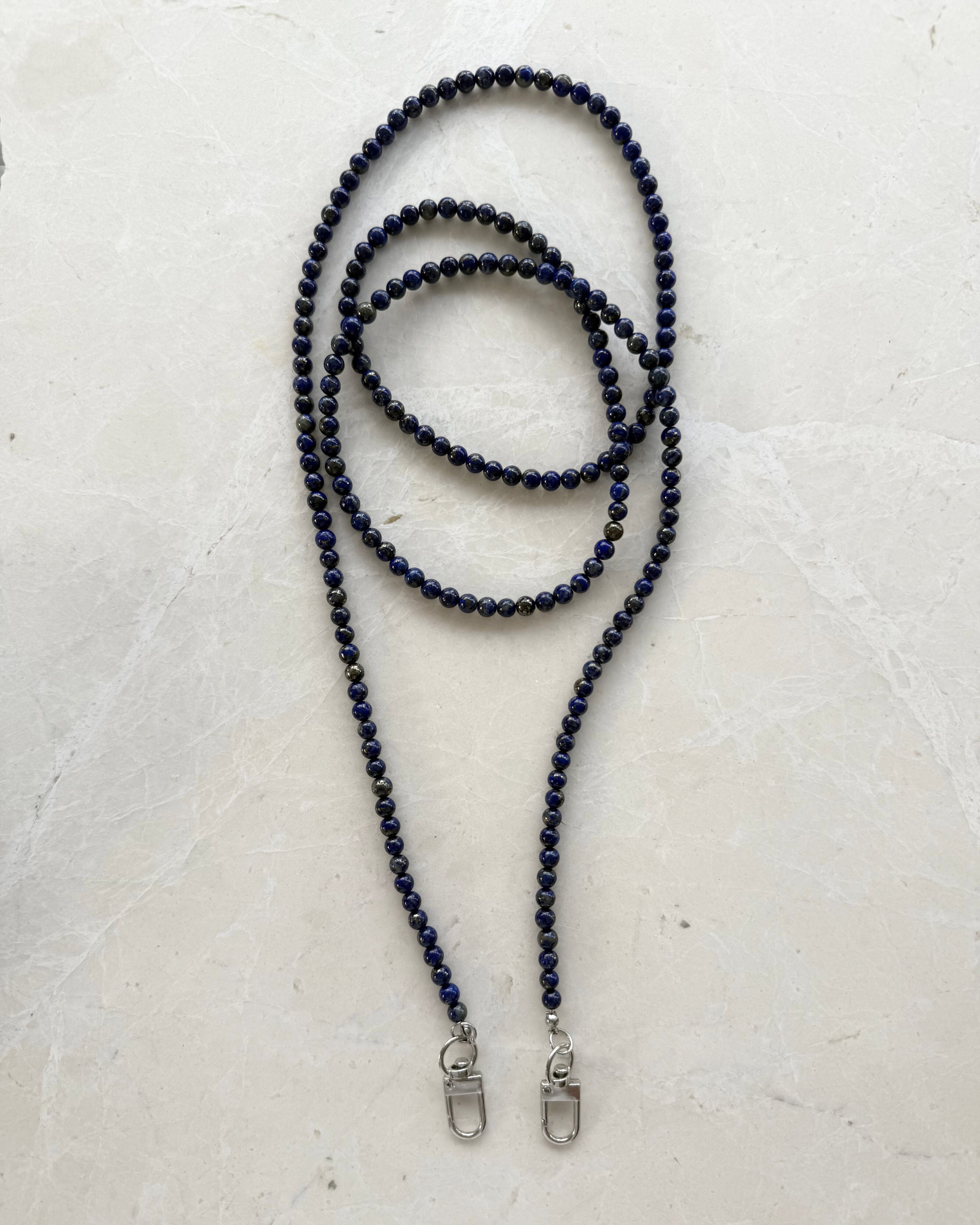 Lapis Lazuli beaded necklace with silver clasp on a light grey background