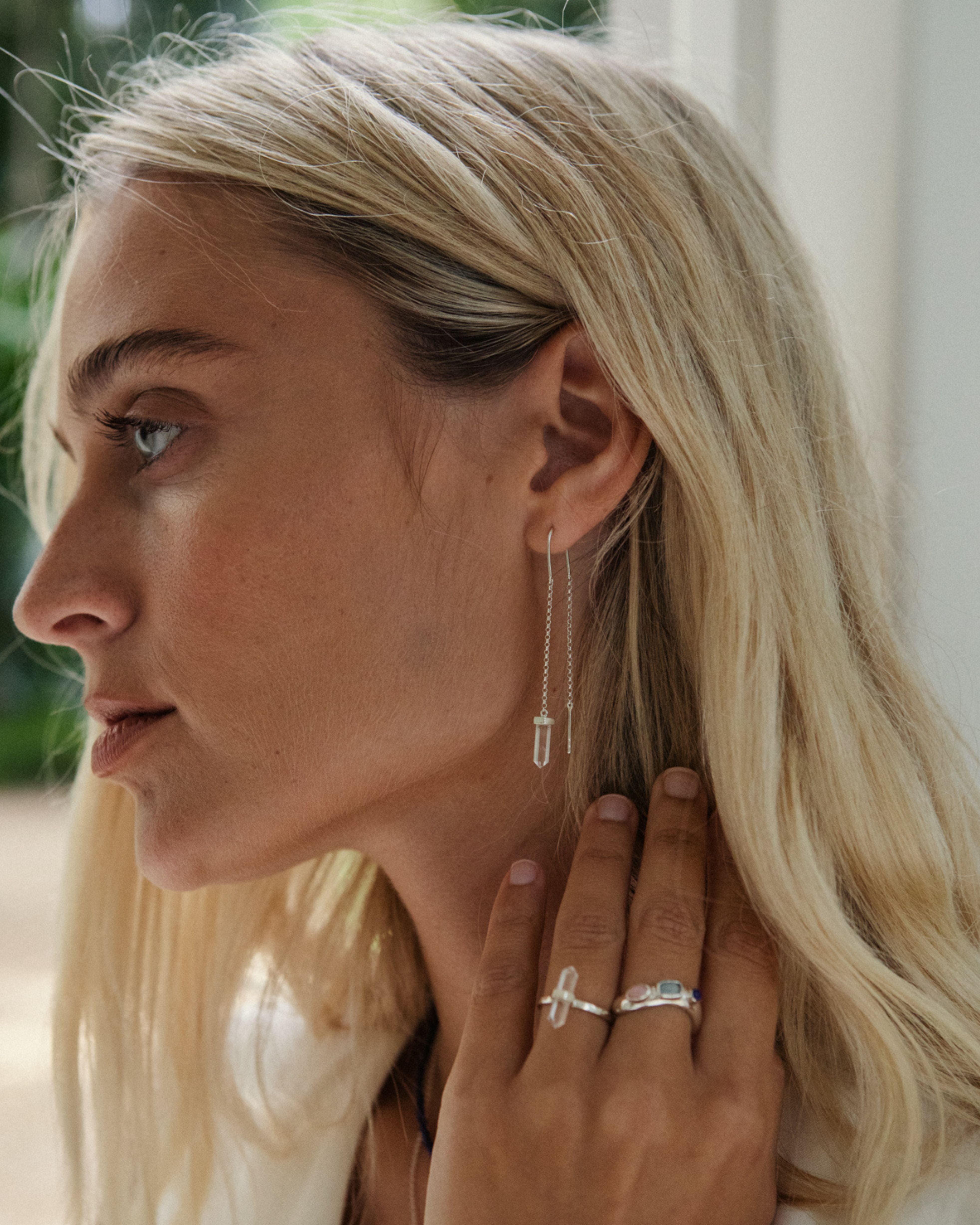 Woman wearing a silver earring and rings, with a blurred background