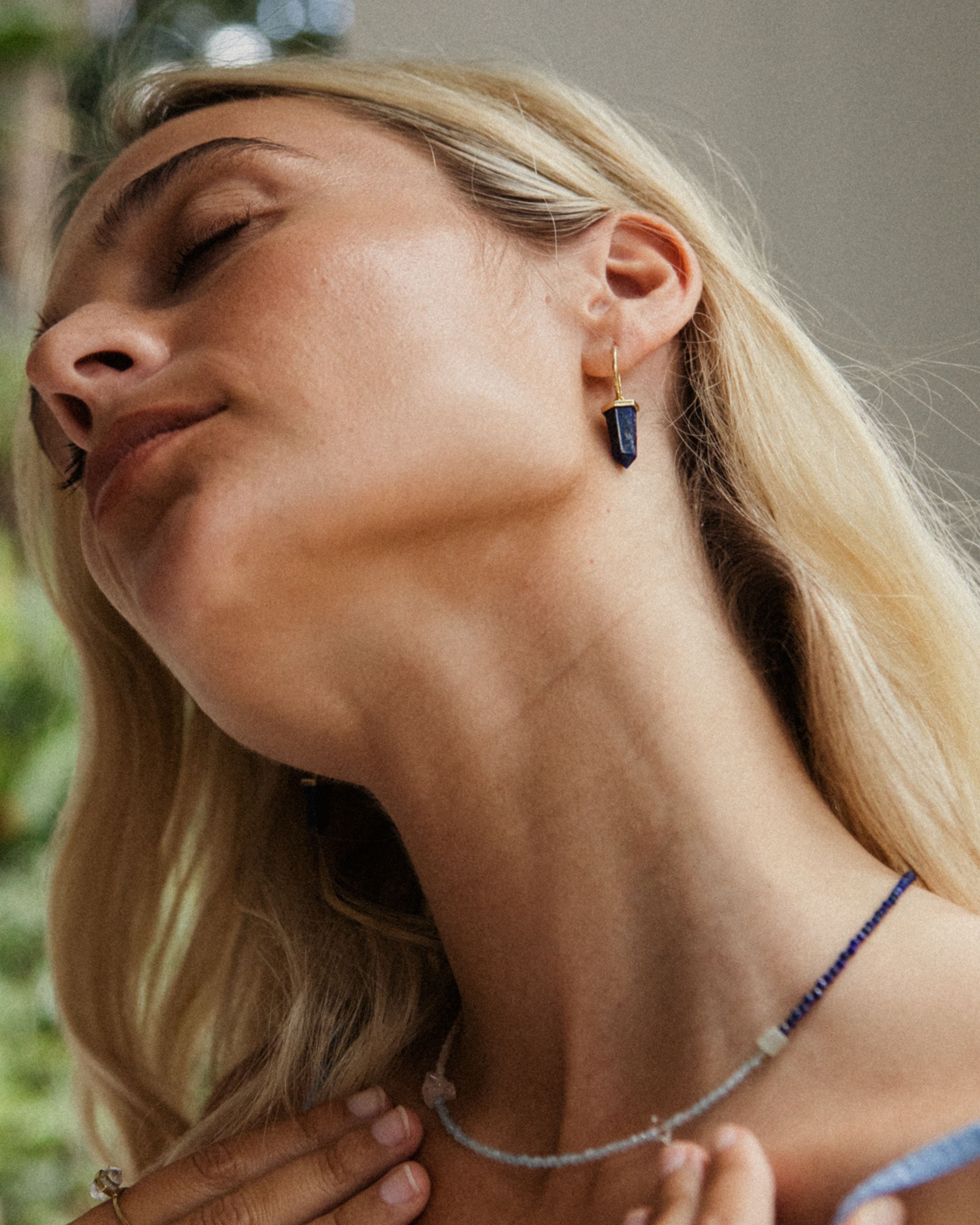 Woman wearing a necklace and earrings with a blurred background