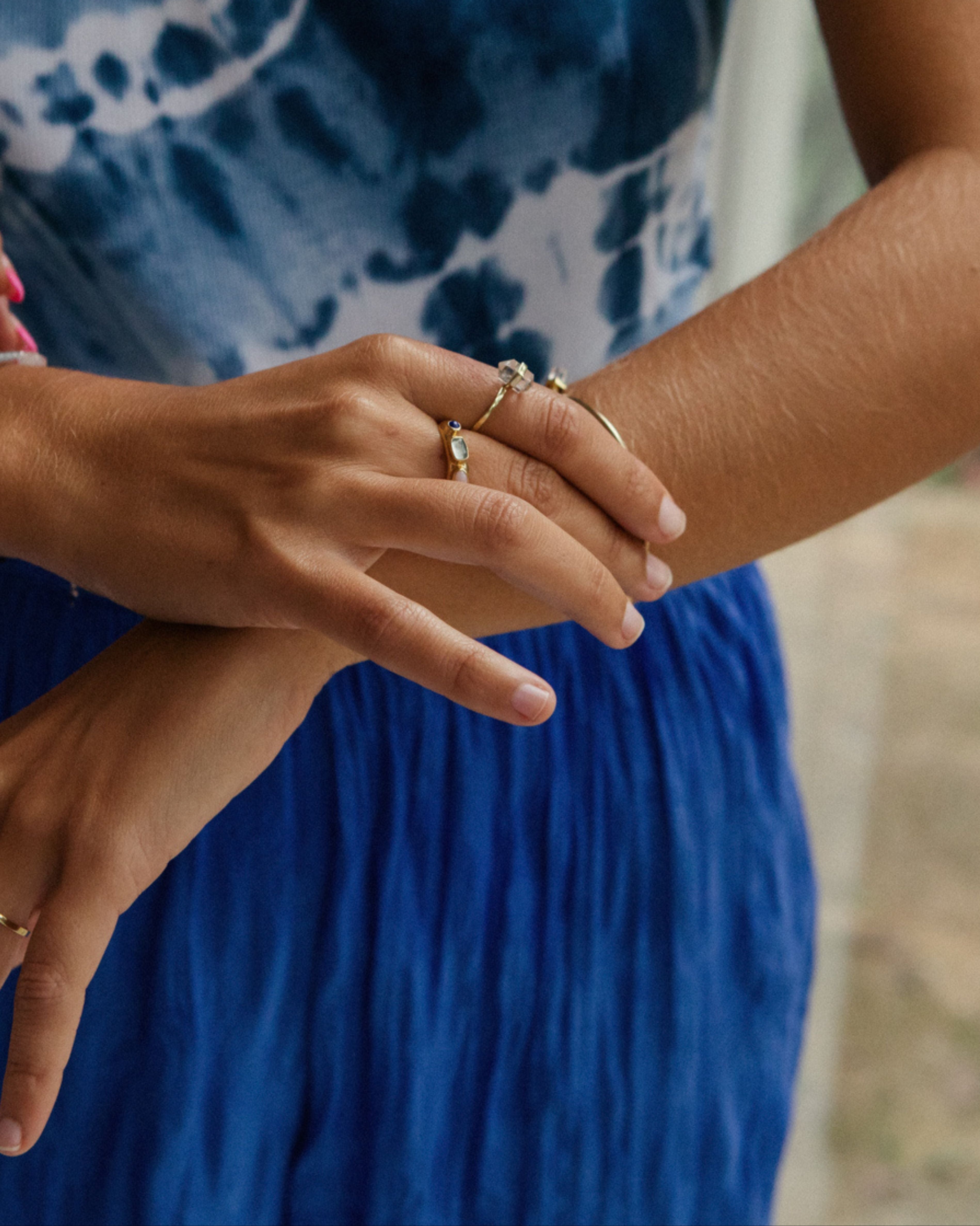 Close-up of hands with rings on a blue fabric background