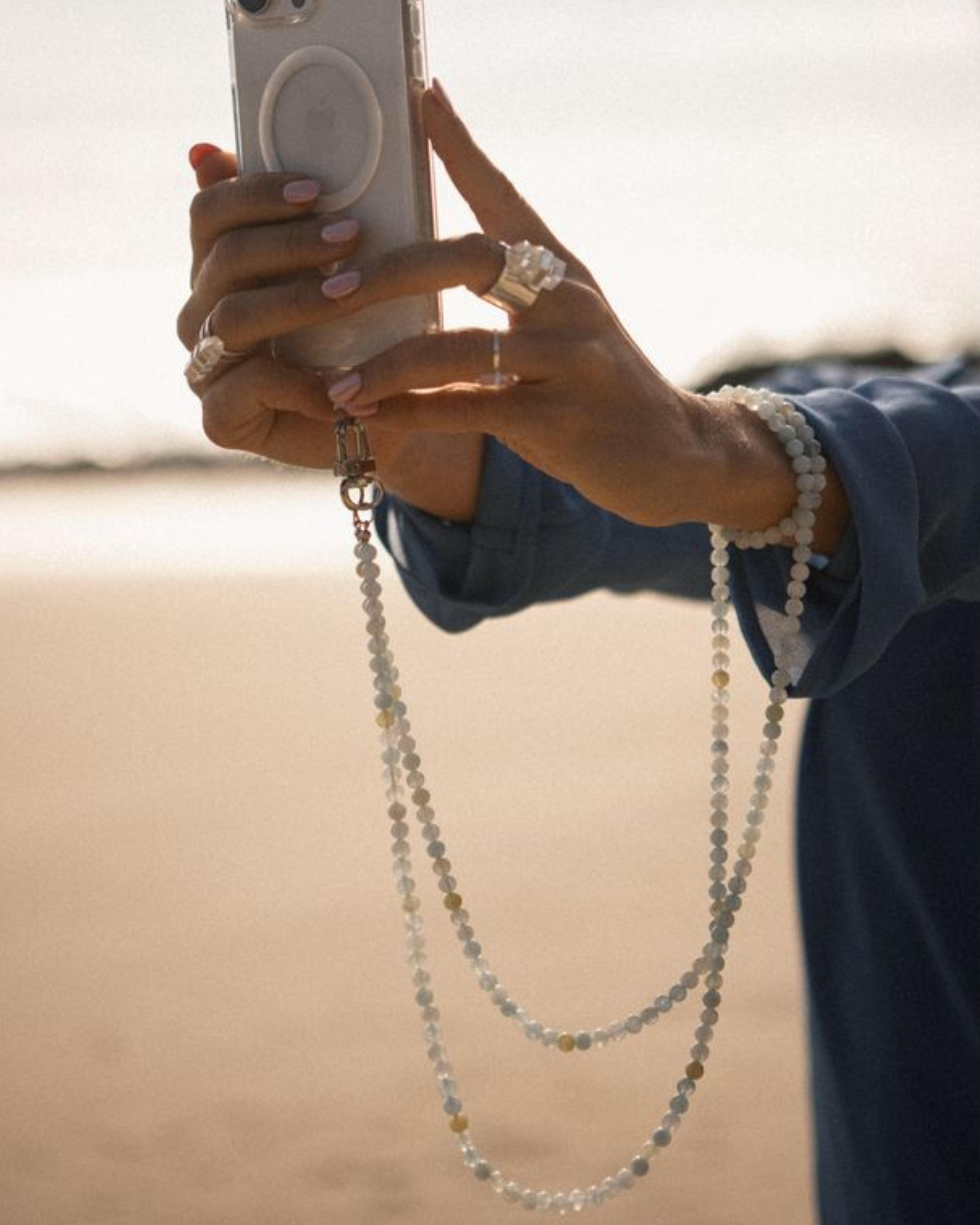 Person holding a phone with a beaded chain, blurred background