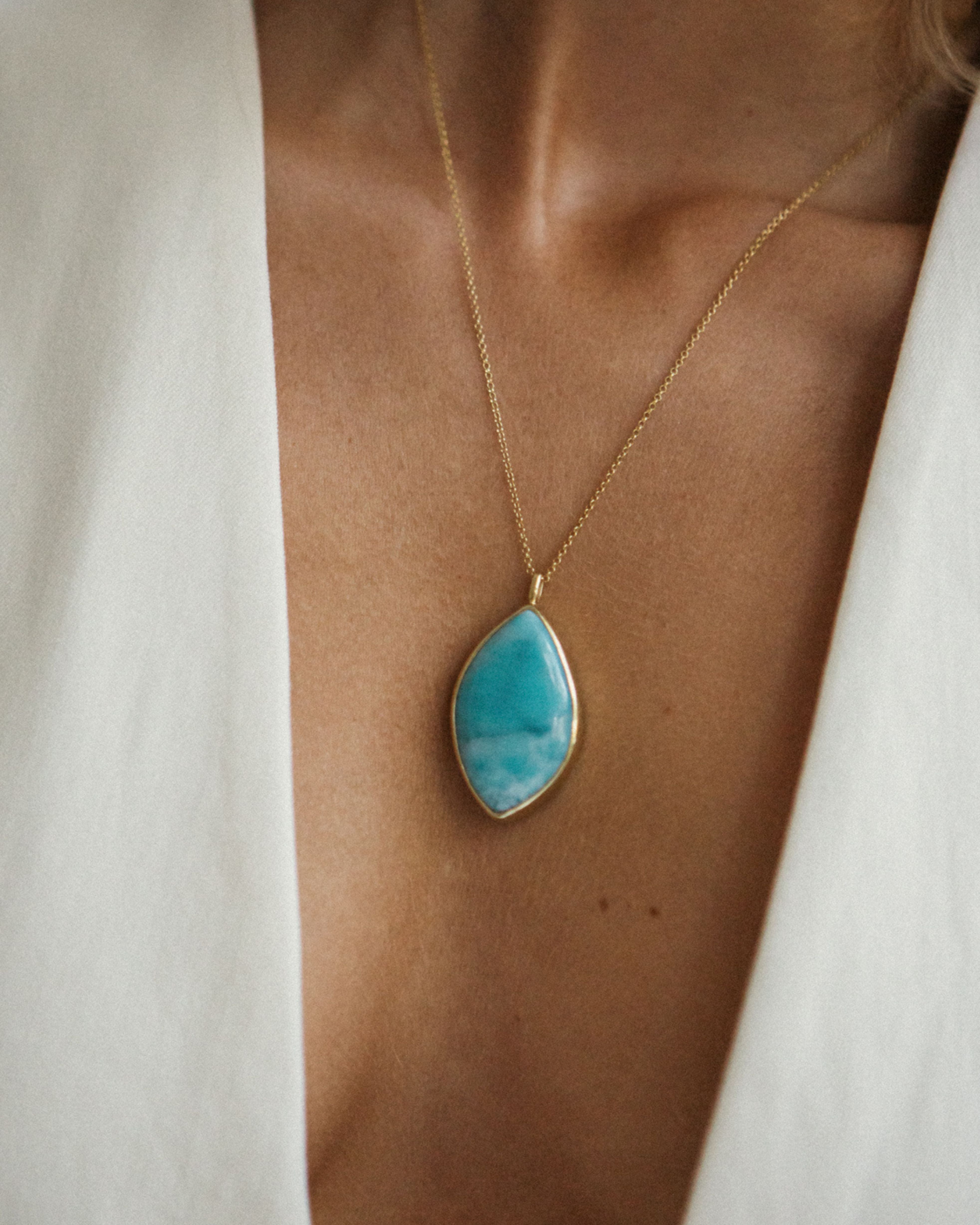 Necklace with a Larimar pendant worn by a person against a neutral background