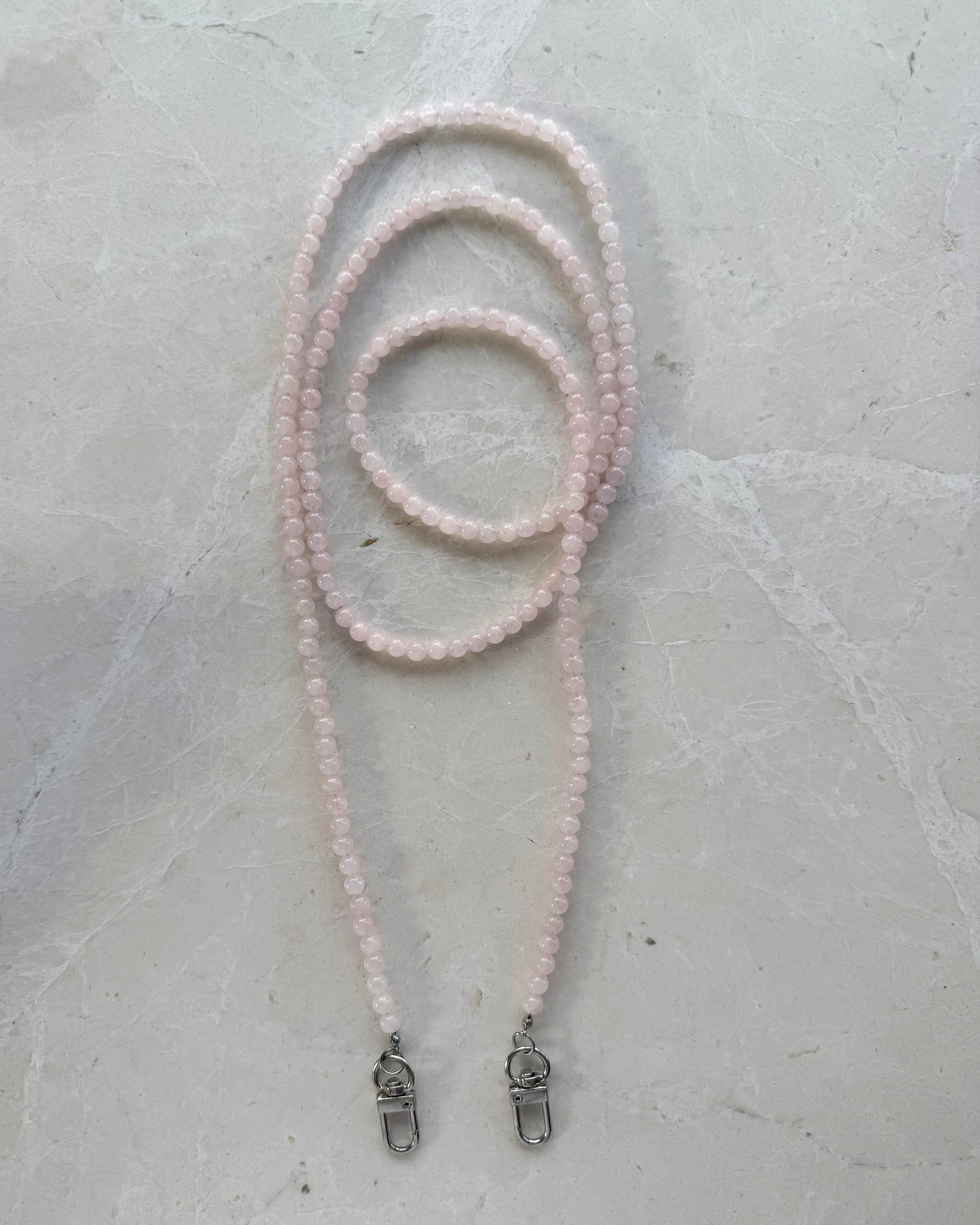 Rose Quartz beaded Phone carrier with metal clips on a grey surface
